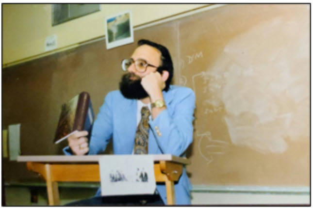 Charles Rosengard at podium, in classroom